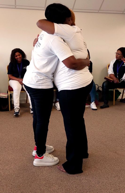Two women embracing in prayer